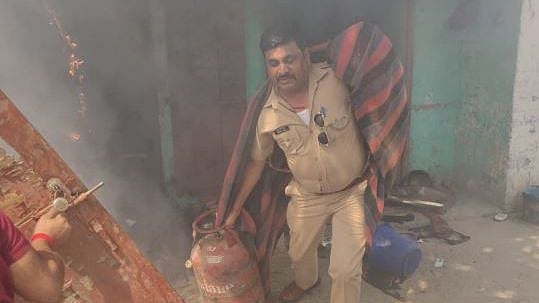 SI Akhilesh Kumar Dixit dragging LPG cylinders out from a house on fire.&nbsp;
