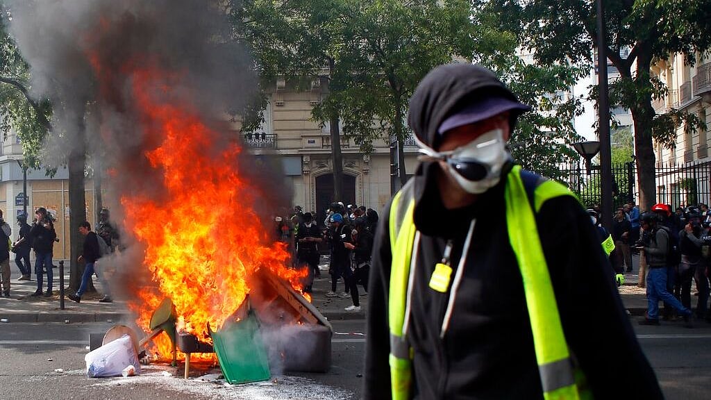 A man walks past garbage that was put on fire in Paris, Wednesday, 1 May 2019. 