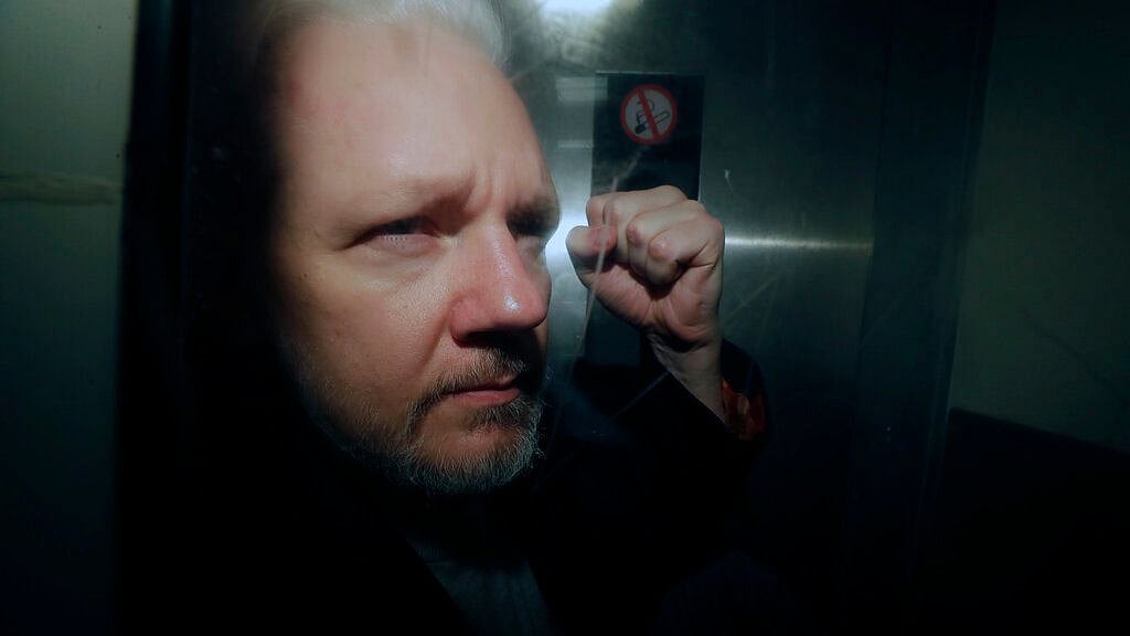 WikiLeaks founder Julian Assange puts his fist up as he is taken from court in London. 