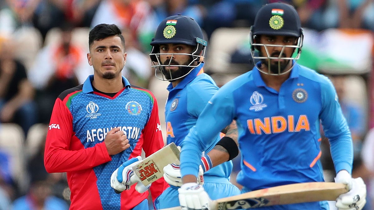 Afghanistan’s Mujeeb Ur Rahman, left, watches as India’s captain Virat Kohli, center, and K.L. Rahul run between the wickets to score.