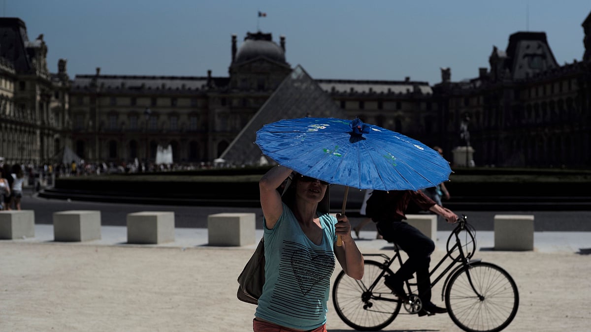 A woman holds a sunshade outside the Louvre Museum in Paris.