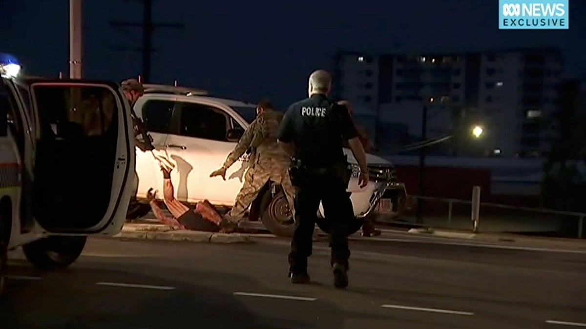 In this image made from a video, police proceed to apprehend a suspect on the ground next to a white truck, Tuesday, 4 June 2019, in Darwin Australia.