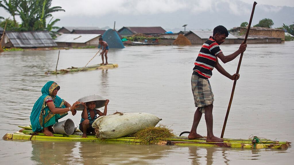 Flood affected villagers move on a makeshift bamboo raft in Katahguri village along the river Brahmaputra, east of Gauhati on Sunday.&nbsp;