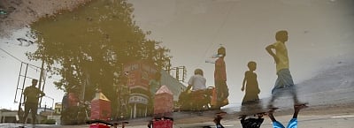 Birbhum: A reflection of children participating in the Bahuda Yatra-the home coming of Lord Jagannath, Lord Balabhadra, Lord Sudarshan and Devi Subhadra from Gundicha Temple to Srimandir; seen in rain water accumulated at a street-side in Bolpur of West Bengal