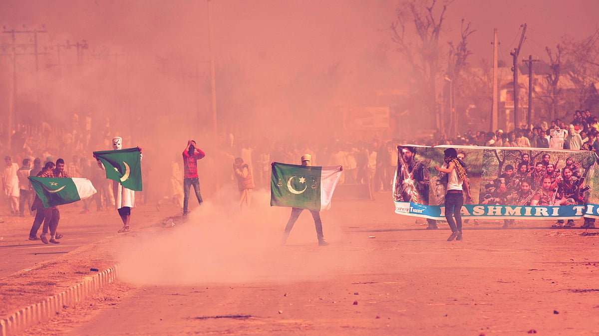 Masked Kashmiris hold the national flag of Pakistan and a banner displaying militant leaders of the Hizb-ul Mujahedeen during a protest. 