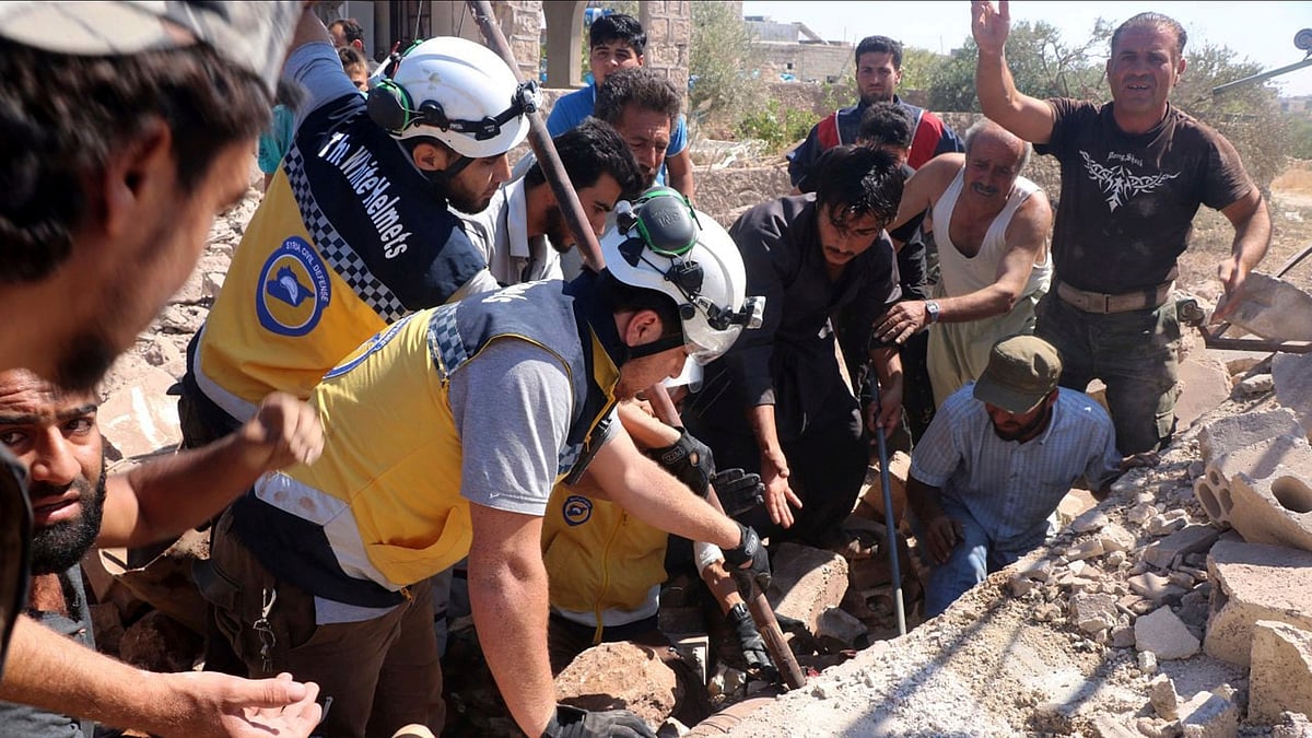 Syrian White Helmet civil defense workers search for victims from under the rubble of a destroyed building that hit by airstrikes, in the northern town of Kfar Rouma, in Idlib province, Syria, 25 July.