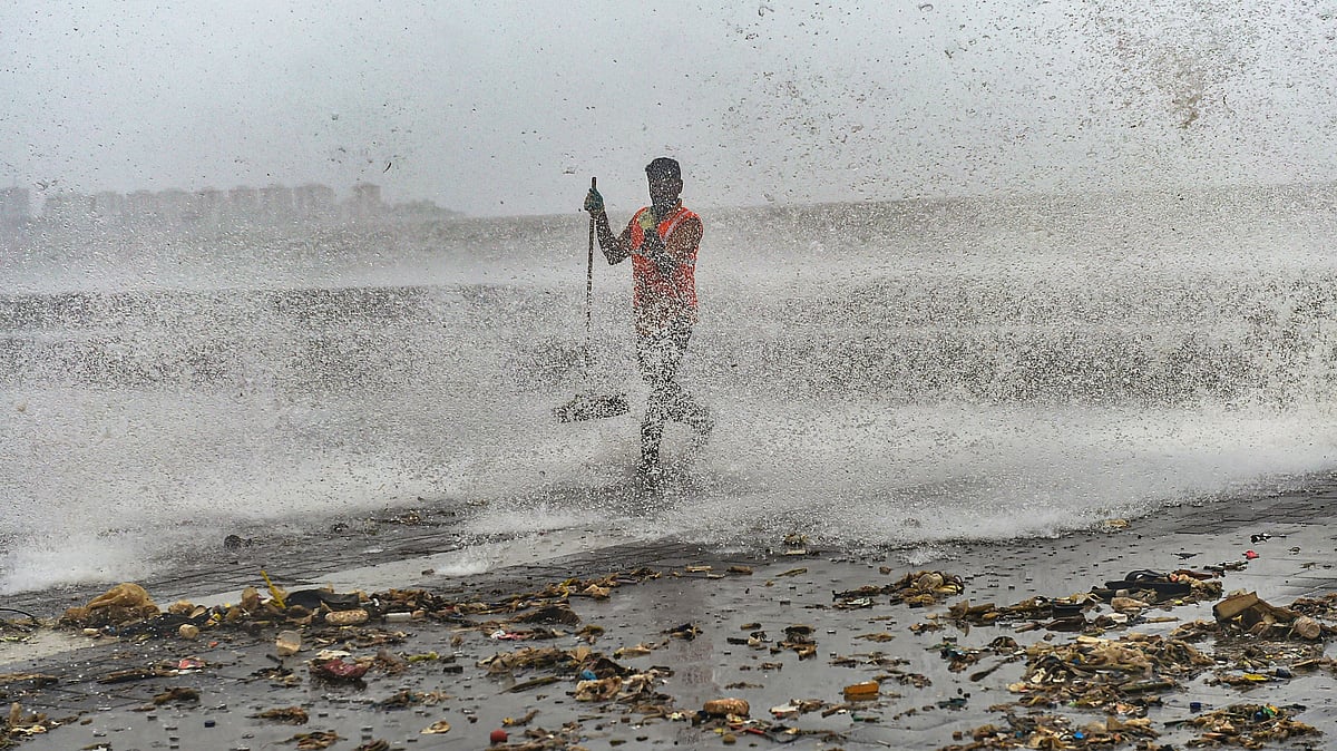 A civic worker clears the plastic waste and garbage thrown out of the sea during a high tide at Marine Drive promenade in Mumbai, on Sunday, 7 July.