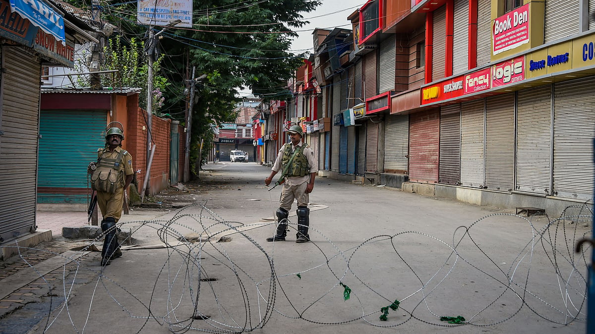 Security personnel stand guard during restrictions in Srinagar on 12 August. 