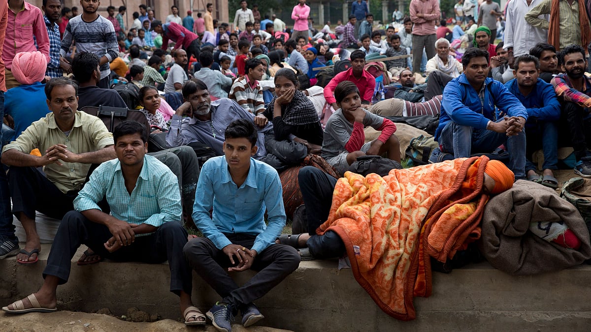 Indian migrant workers wait outside the government transport yard, waiting to buy bus tickets to leave the region, during curfew in Srinagar.