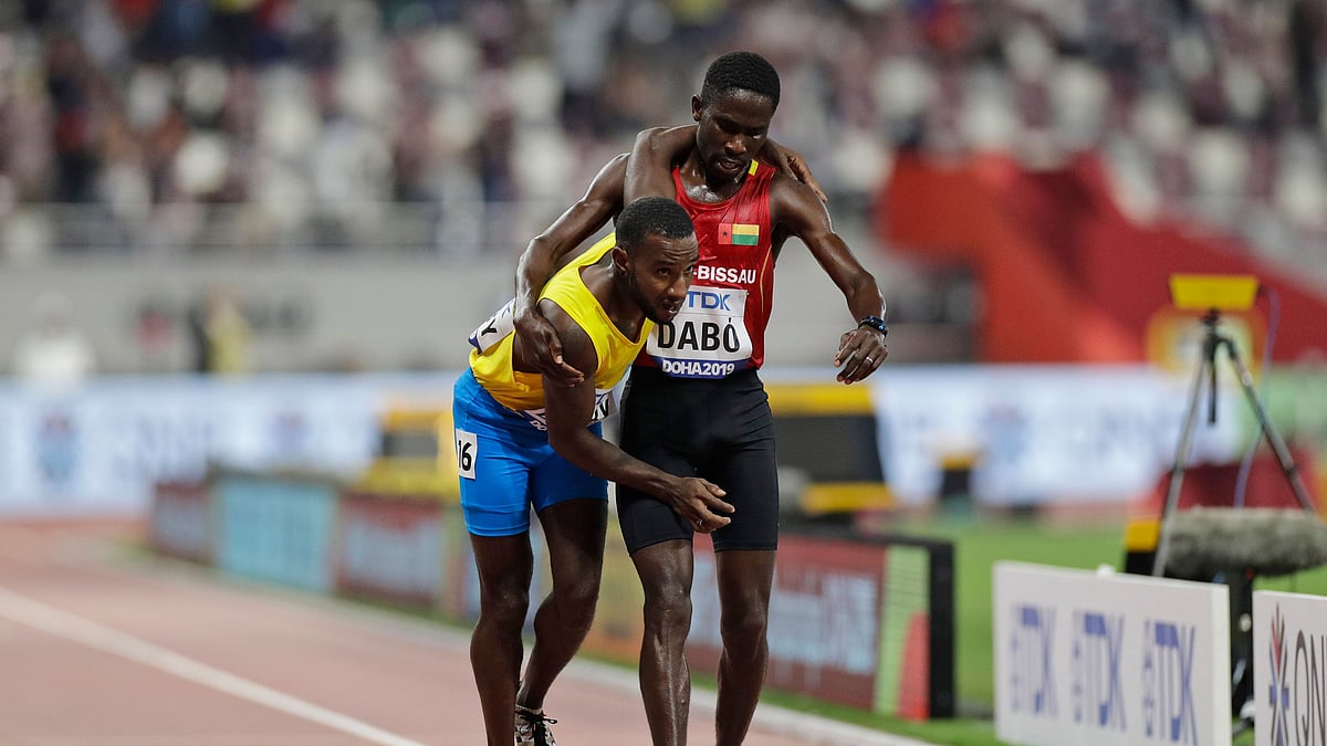 Braima Suncar Dabo of Guinea Bissau carries Jonathan Busby of Aruba to the finish line during the men’s 5,000 meters heats during the World Athletics Championships Friday, Sept. 27, 2019, in Doha, Qatar. 