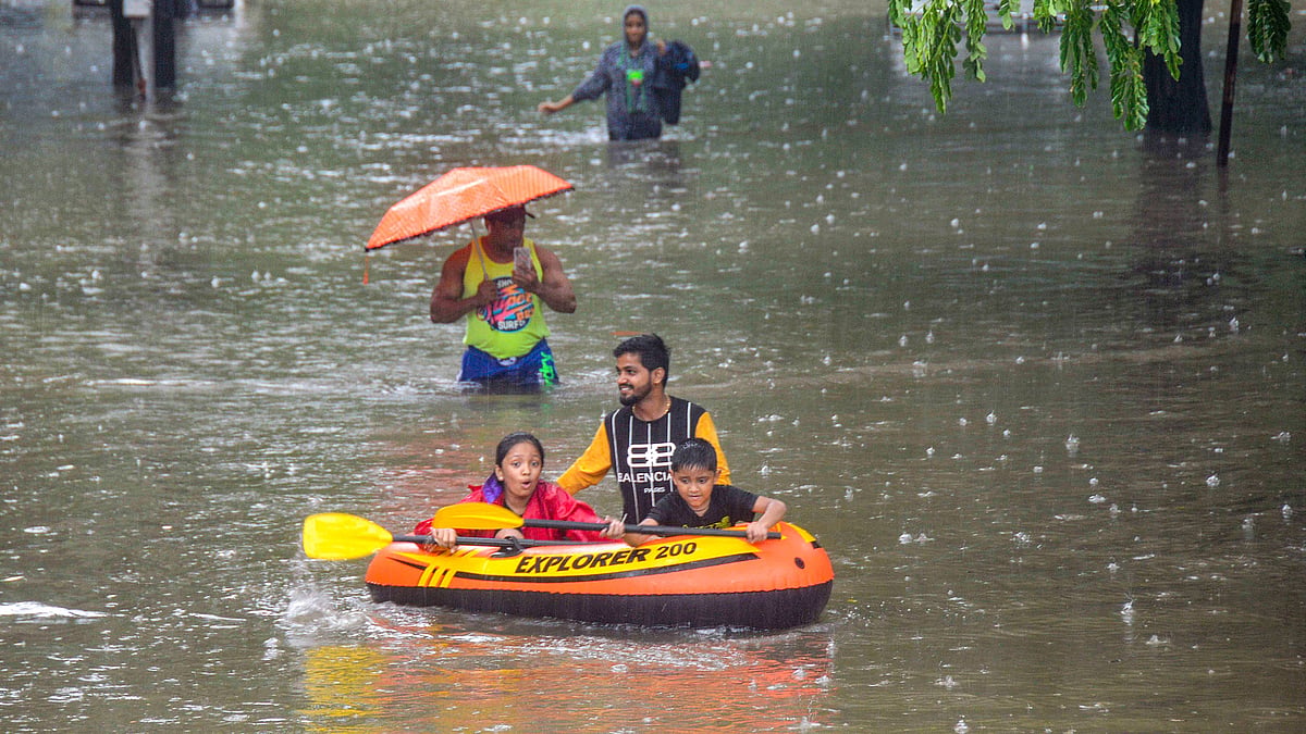 People commute through a waterlogged street on foot and via inflatable boat, following heavy monsoon rain in Mumbai on Wednesday.
