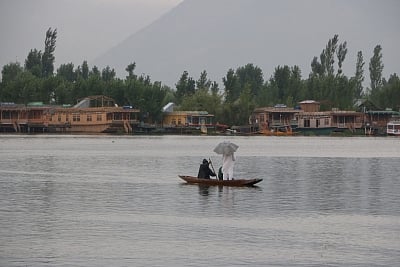 Srinagar: A man enjoys boat ride in the Dal Lake amidst rains in Srinagar on July 18, 2019. (Photo: IANS)