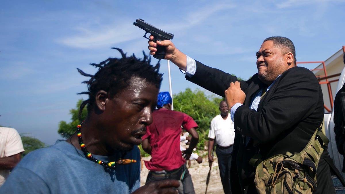 Ruling party Senator Ralph Fethiere fires his gun outside Parliament in Haiti