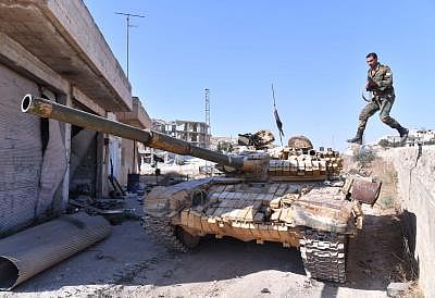 IDLIB (SYRIA), Aug. 24, 2019 (Xinhua) -- A Syrian soldier jumps onto a tank in the town of Khan Shaykhun in the southern countryside of Idlib province, Syria, on Aug. 24, 2019. The Syrian army on Friday fully secured the entire northern countryside of the central province of Hama for the first time since 2012, the state media reported. (Photo by Ammar Safarjalani/Xinhua/IANS)