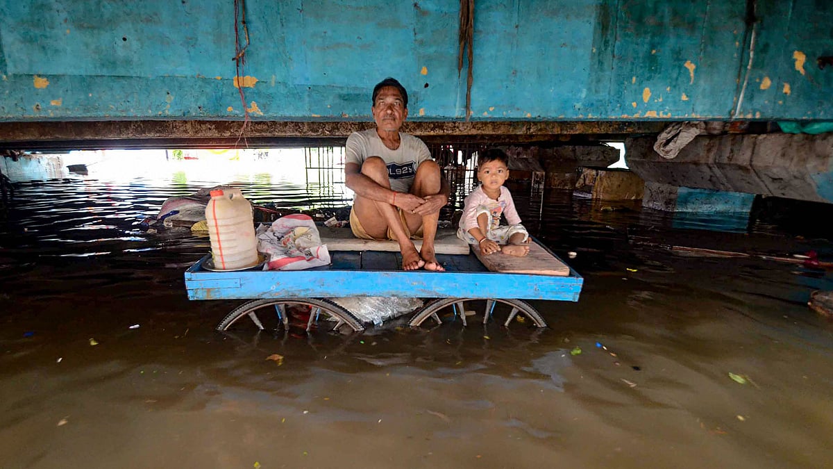 A person sits with a child on a cart in an area affected by waterlogging following heavy monsoon rainfall in Patna on Monday, 30 September.