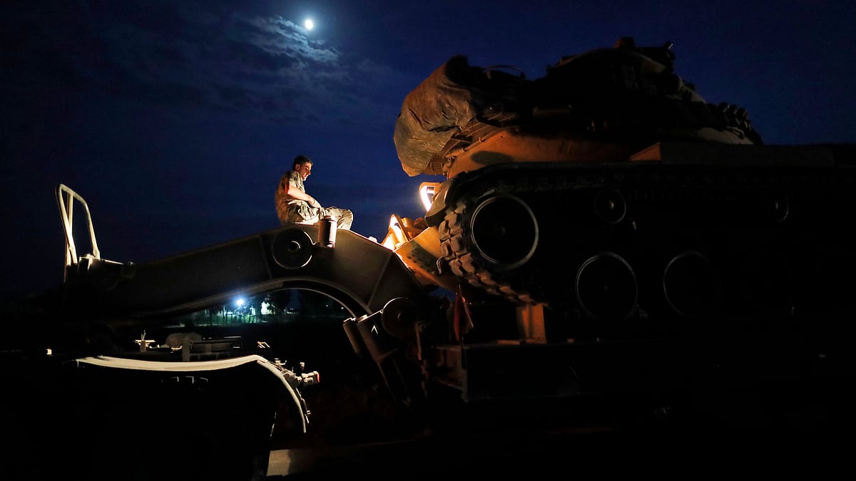 A Turkish army officer prepares to upload a tank from a truck to its new position on the Turkish side of the border between Turkey and Syria, in Sanliurfa province, southeastern Turkey.