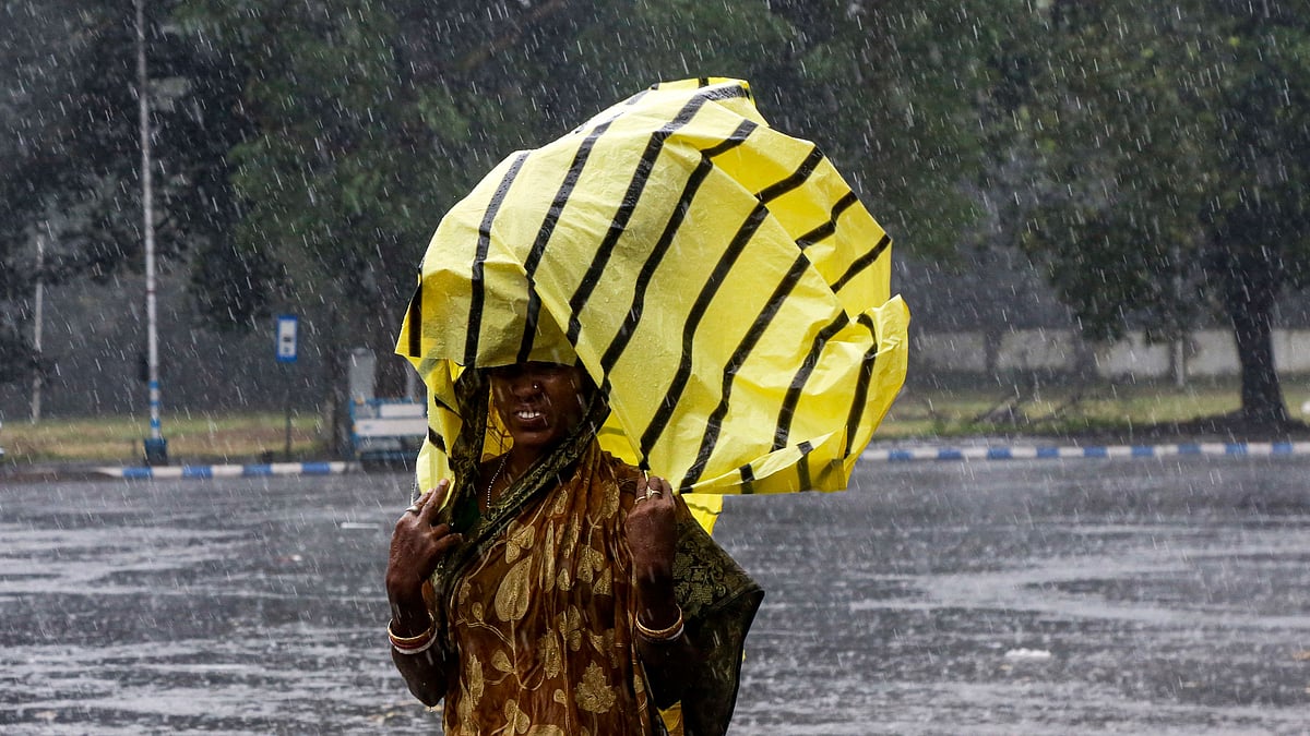 A woman covers her head with a plastic sheet as it rained in Kolkata. 