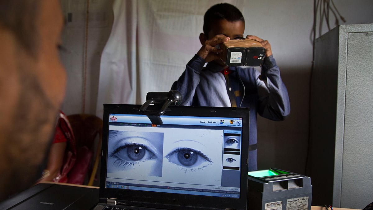 A National Register of Citizens (NRC) officer takes a photograph of the eyes of a boy at an NRC center. 