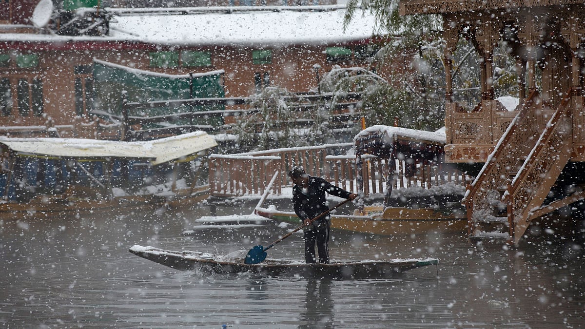 A man rows his boat as it snows in Srinagar on Thursday.&nbsp;