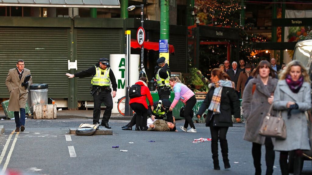 A person is assisted after falling when Police evacuated people from Borough Market on the south side of London Bridge in London, Friday, 29 November, 2019.