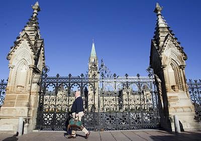 Ottawa: A man passes the closed door of Parliament buildings in Ottawa, Canada, Oct. 23, 2014. Canada is not immune to terror attacks but not intimidated by terrorism, Prime Minister Stephen Harper said Wednesday after a gunmen attacked the parliament and killed a soldier earlier in the day. (Xinhua/Zou Zheng/IANS)
