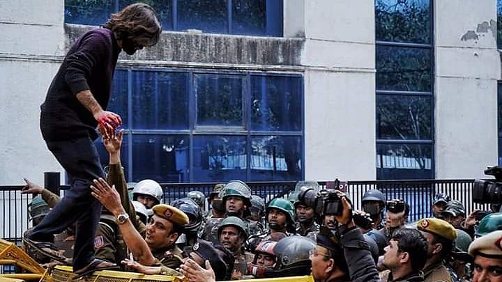 Injured Shadab Farooq climbs over the barricades, in order to get medical help.