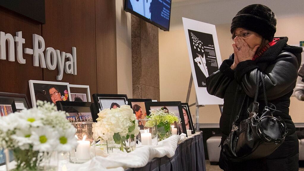 A woman pauses at a memorial prior to a ceremony in Montreal, Sunday,19 January 2020, to remember those who lost their lives in a Ukraine airplane crash in Iran on 8 January.