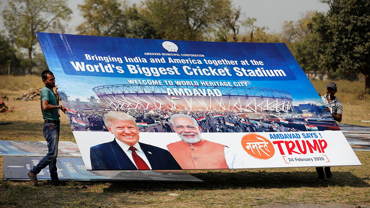 Workers carry a hoarding with pictures of the US President Donald Trump and Prime Minister Narendra Modi in Ahmedabad.