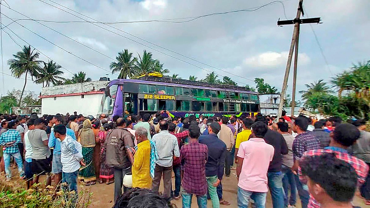 People look on to the bus which caught fire after coming in contact with a power transmission line at Golanthara .