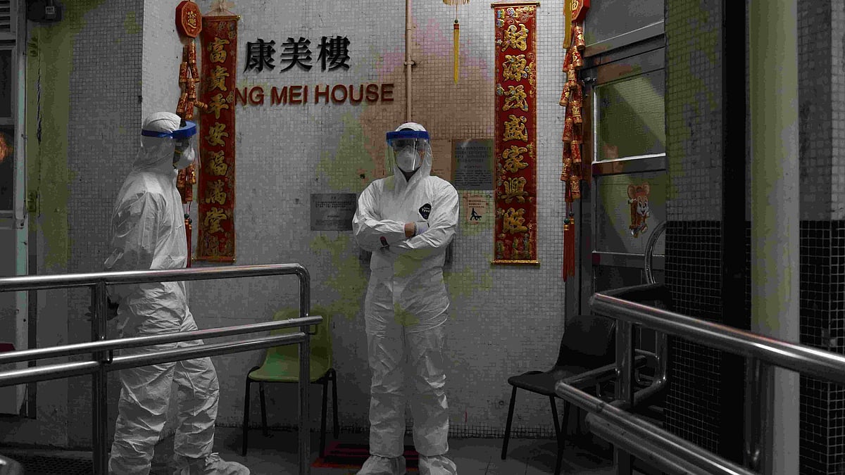 People wearing protective suits stand near an entrance at the Cheung Hong Estate during evacuation of residents in Hong Kong on 11 February. 