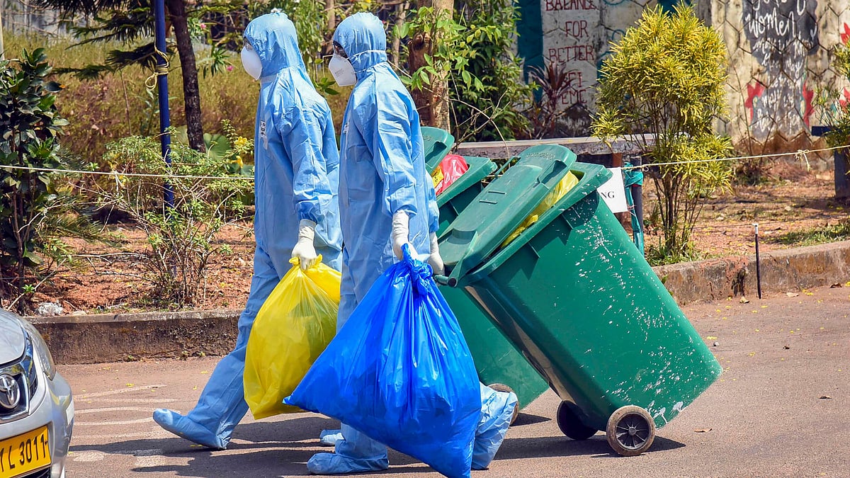 Medical staff, wearing protective suits, hold medical waste as they exit the Special Isolation Ward set up to provide treatment to novel coronavirus patients at Kochi Medical college, in Kerala.
