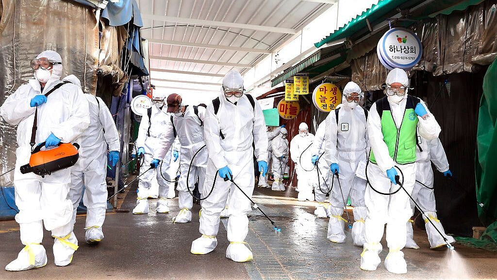 Workers wearing protective suits spray disinfectant as a precaution against the coronavirus at a market in Bupyeong, South Korea.