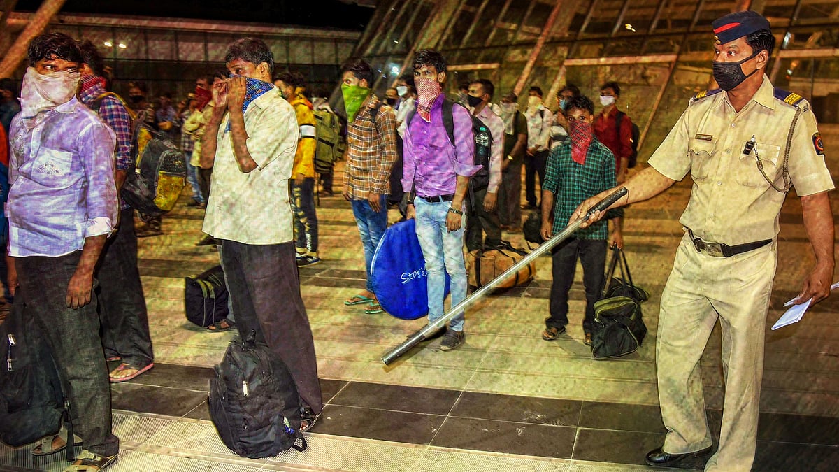  A police constable guides migrants who were travelling to native places at midnight during a nationwide lockdown in the wake of coronavirus pandemic, in Navi Mumbai, Sunday, 29 March, 2020.