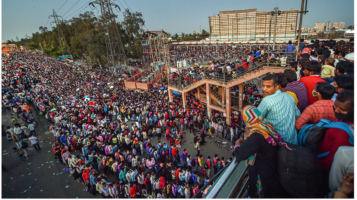 Migrants wait to board a bus to their native villages, during a nationwide lockdown imposed in the wake of coronavirus pandemic, at Kaushambi in Ghaziabad, Saturday, March 28, 2020.