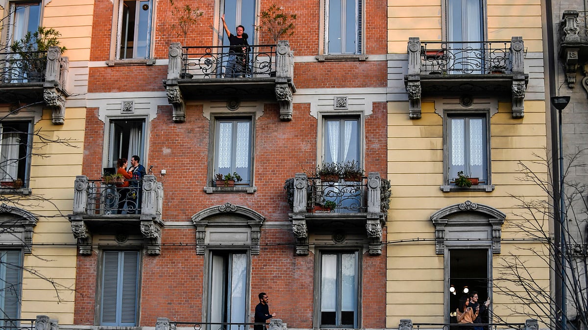 People stand on their balconies during one of the many flash mobs taking place these days in Milan, Italy, Sunday, 15 March 2020.