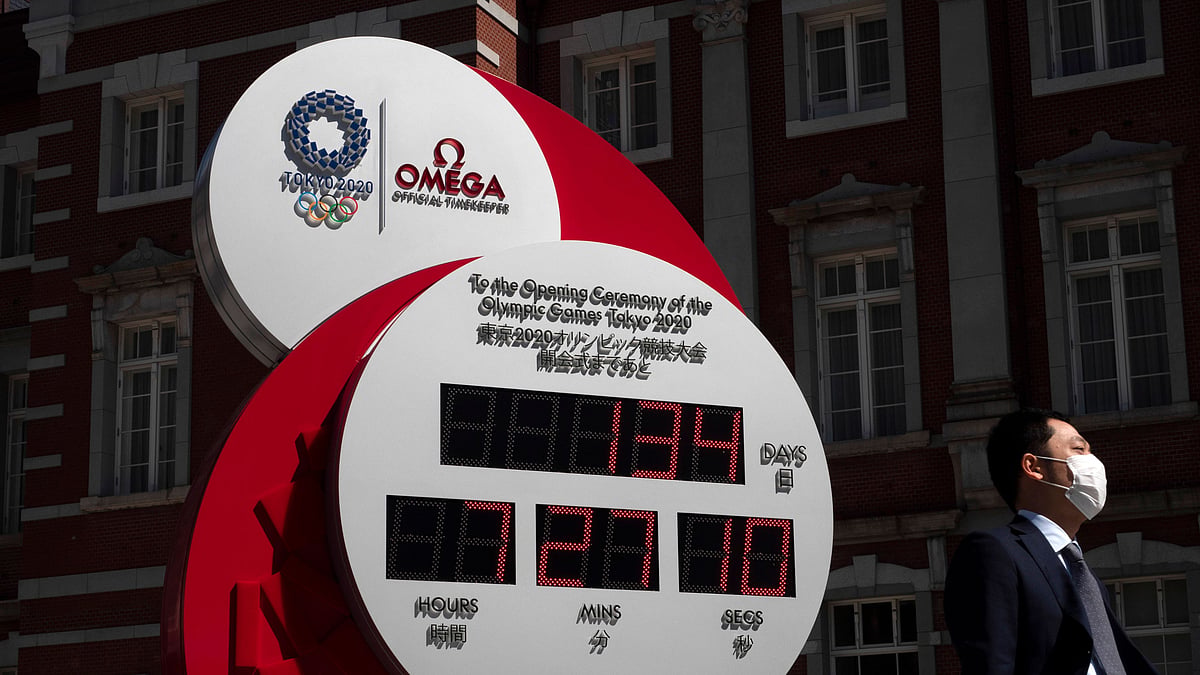 A man with a mask walks past a countdown clock for the Tokyo 2020 Olympics Thursday, 11 March.