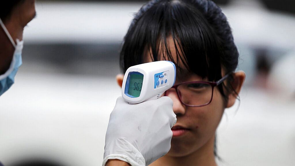 A girl is measured the body temperature by a member of Yangon City Development Committee during a public awareness for prevention of the novel coronavirus at a market in Yangon, Myanmar.