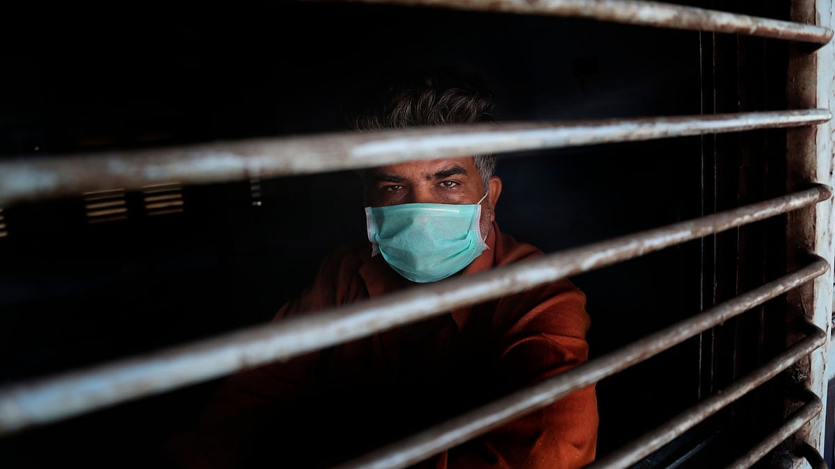 A railways employee wearing a mask looks out from the window of a train at Chhatrapati Shivaji Maharaj Terminus in Mumbai, on Wednesday, 25 March.