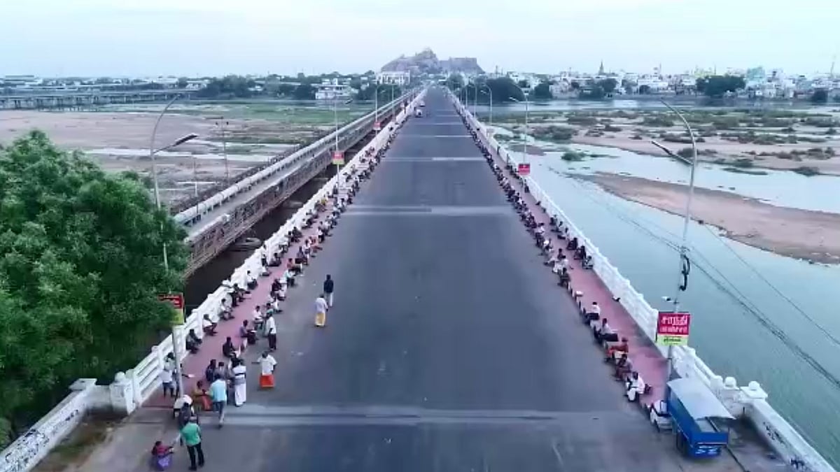 A long stretch of hundreds of people sitting on the bridge over the Cauvery river in Trichy, Tamil Nadu waiting for food to be served. 