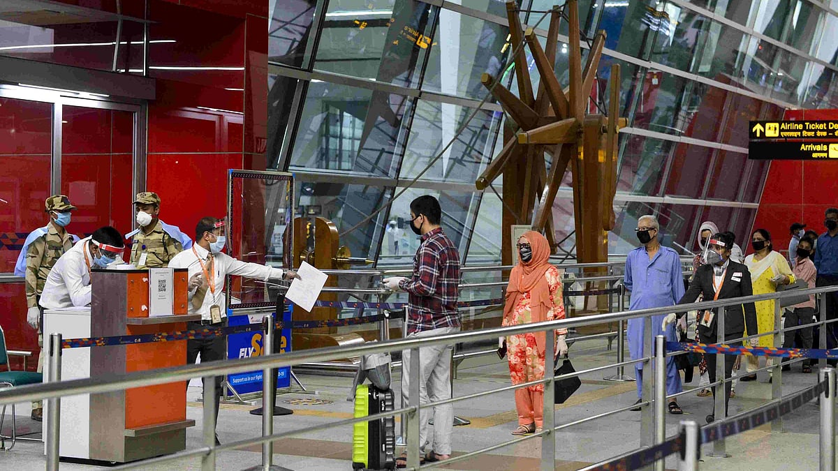 Passengers stand in a queue as they arrive at T-3 airport for domestic travel in New Delhi on 25 May.