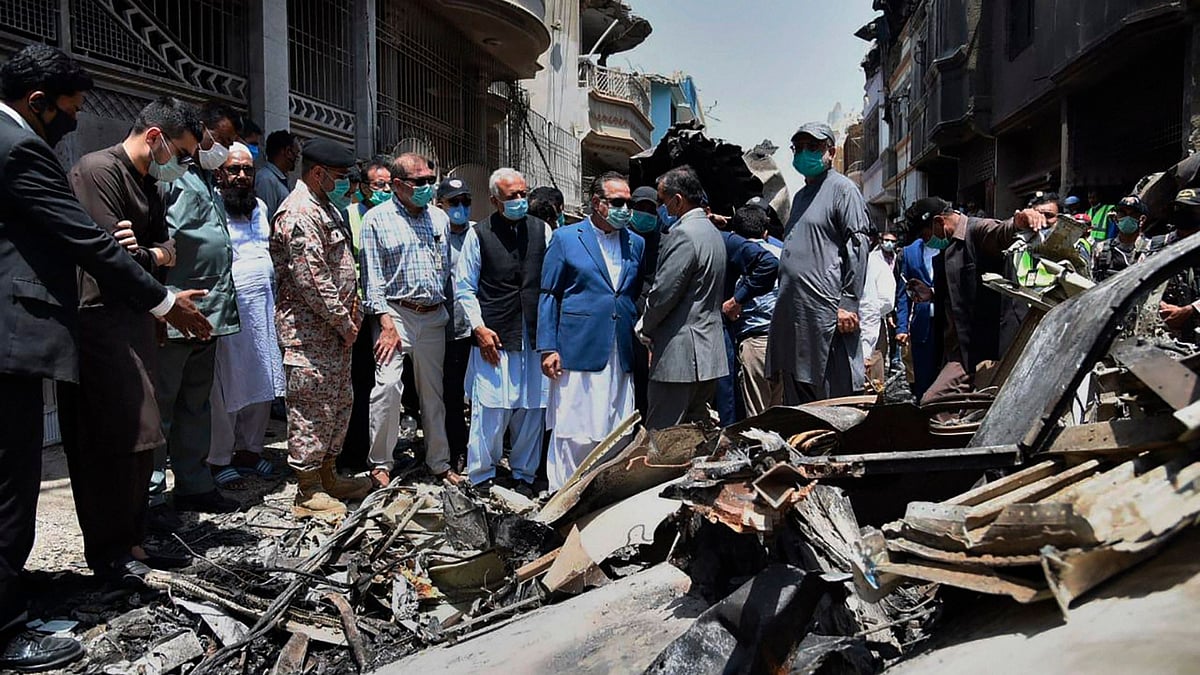 In this photo released by Pakistan Civil Aviation Authority, Provincial Governor Imran Ismail and Pakistan's Aviation Minister Ghulam Sarwar visit the site of Friday's plane crash, in Karachi, Pakistan on Saturday, 23 May. 