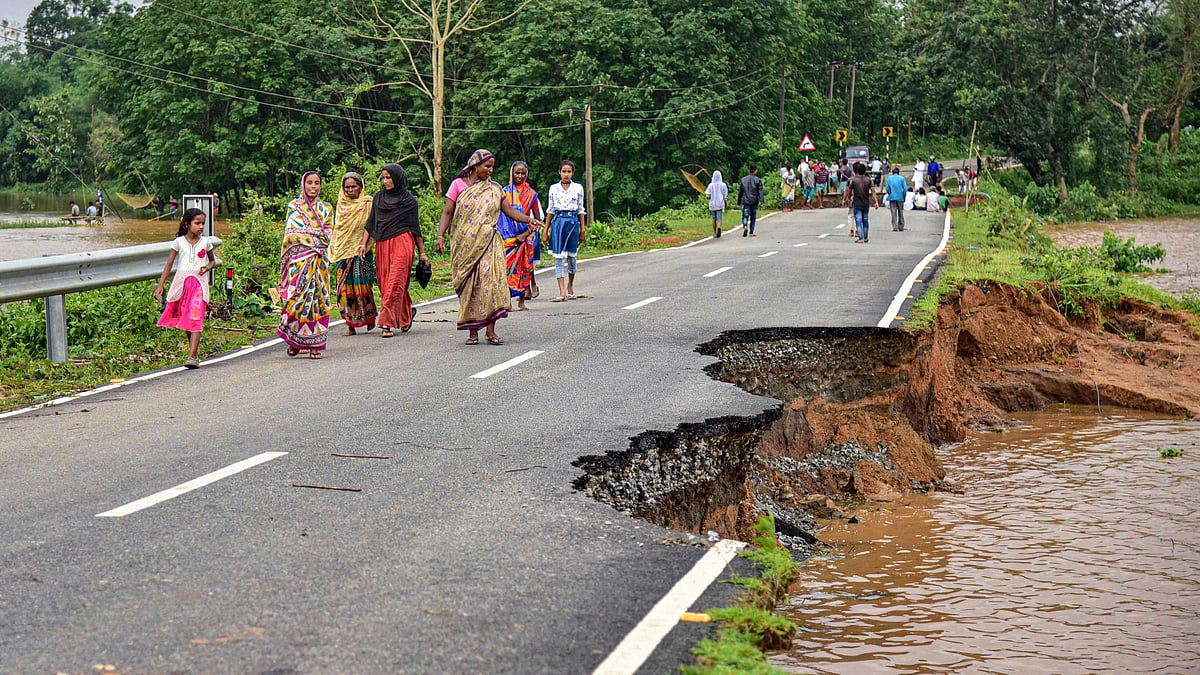 Villagers walk on a road that is partially damaged and washed away due to floods following heavy rainfall, in Goalpara district of Assam on Monday, 25 May.