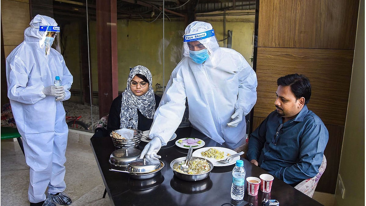 Waiters wearing PPE kits serve food to cusromers at a restaurant in Patna.