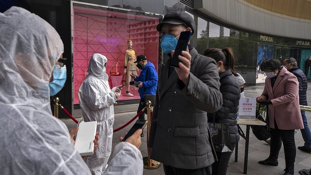 Workers wearing protective suits check customers’ health QR codes at the entrance of a re-opened shopping mall in in Wuhan in central China’s Hubei province.