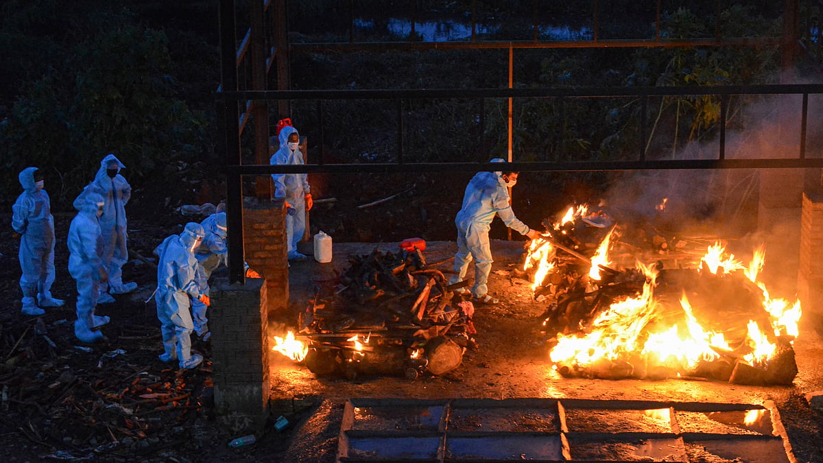 Municipal workers and family members wearing protective suits cremate the body of a COVID-19 patient. Image for representative purposes.