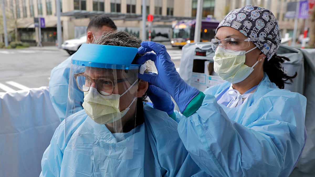 An emergency services nurse helps a colleague put on a medical face shield. Image used for representation.