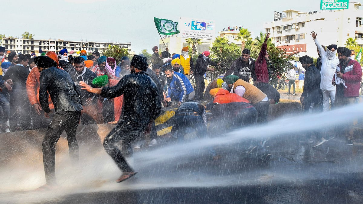 Police personnel use water canons on farmers to stop them from crossing the Punjab-Haryana border during Delhi Chalo protest march against the new farm laws, near Ambala