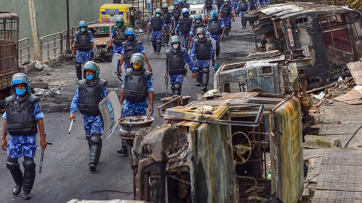 Rapid Action Force (RAF) personnel carry out a flag march in the riot-hit area after a mob went on a rampage on 11 August over a social media post, allegedly posted by a Congress MLAs relative, in Bengaluru.