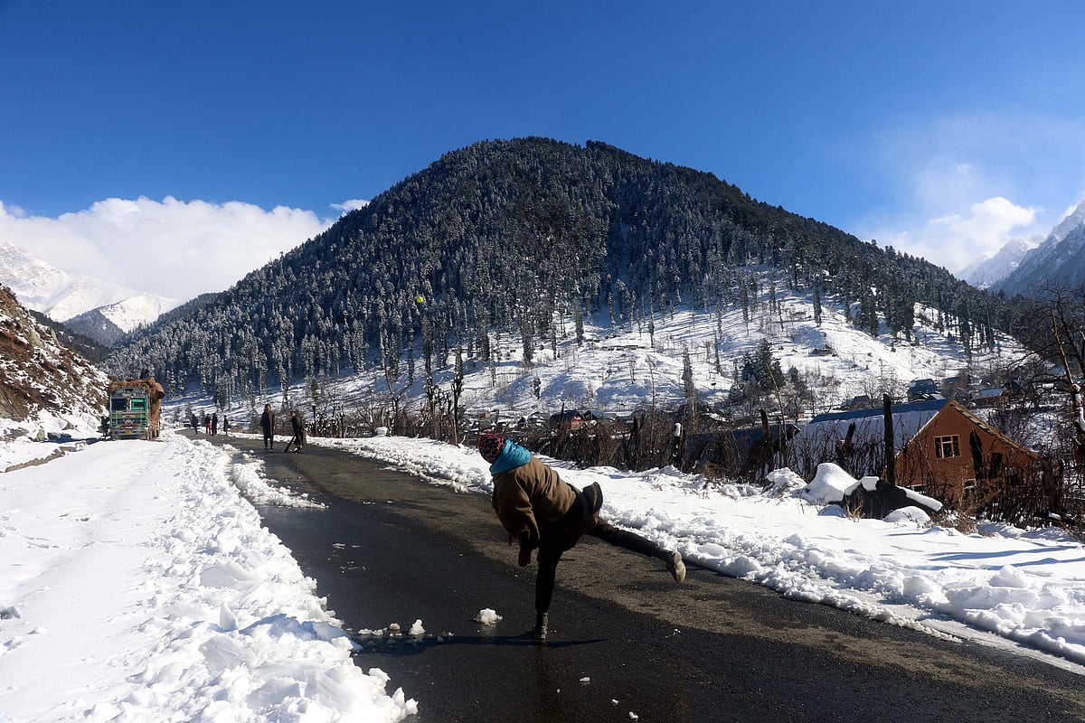 Boys playing cricket with snow-covered mountains in the surroundings.