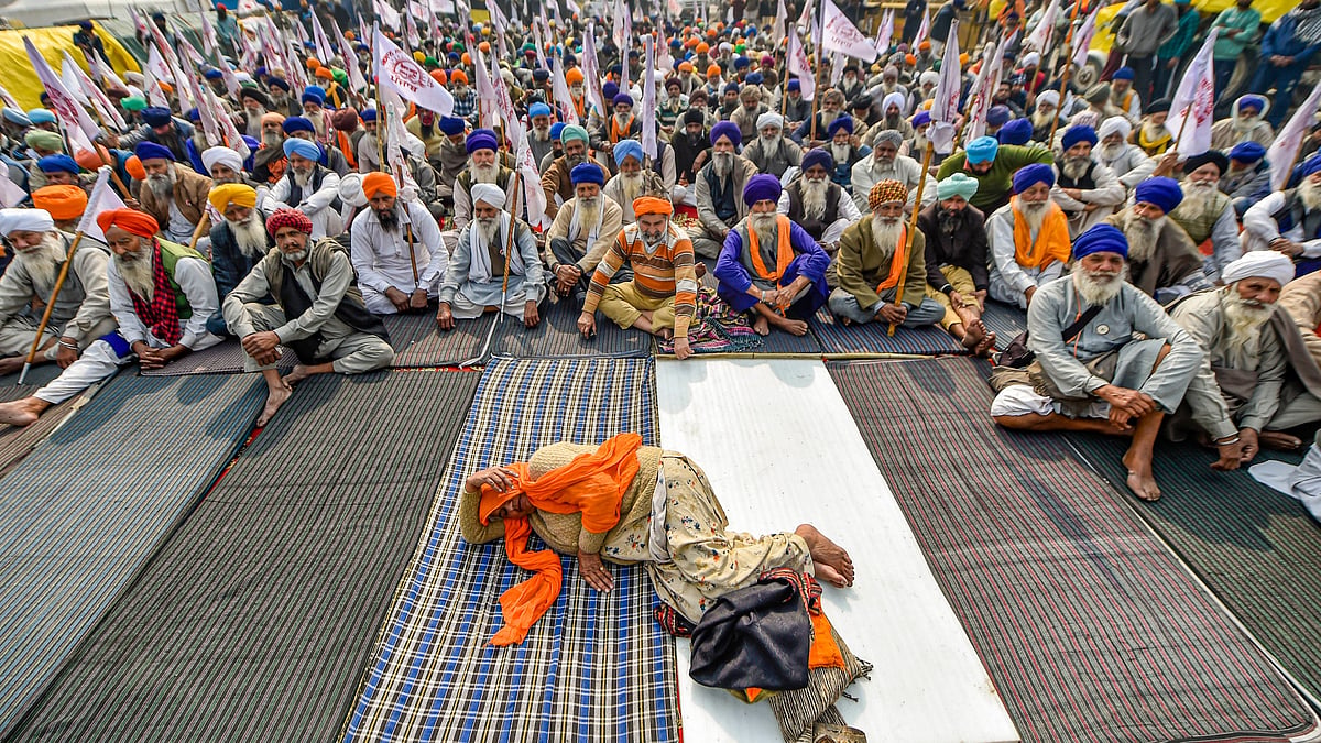 A woman rests as farmers raise slogans at Singhu border during their ongoing agitation against Centres farm reform laws, in New Delhi, Thursday, 28 January, 2021.